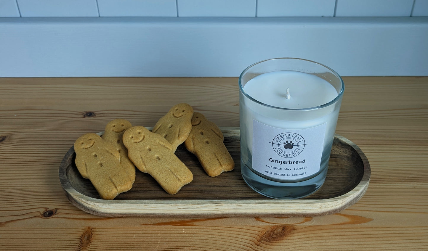 Gingerbread candle sat on wooden tray with 5 gingerbread men surrounding it