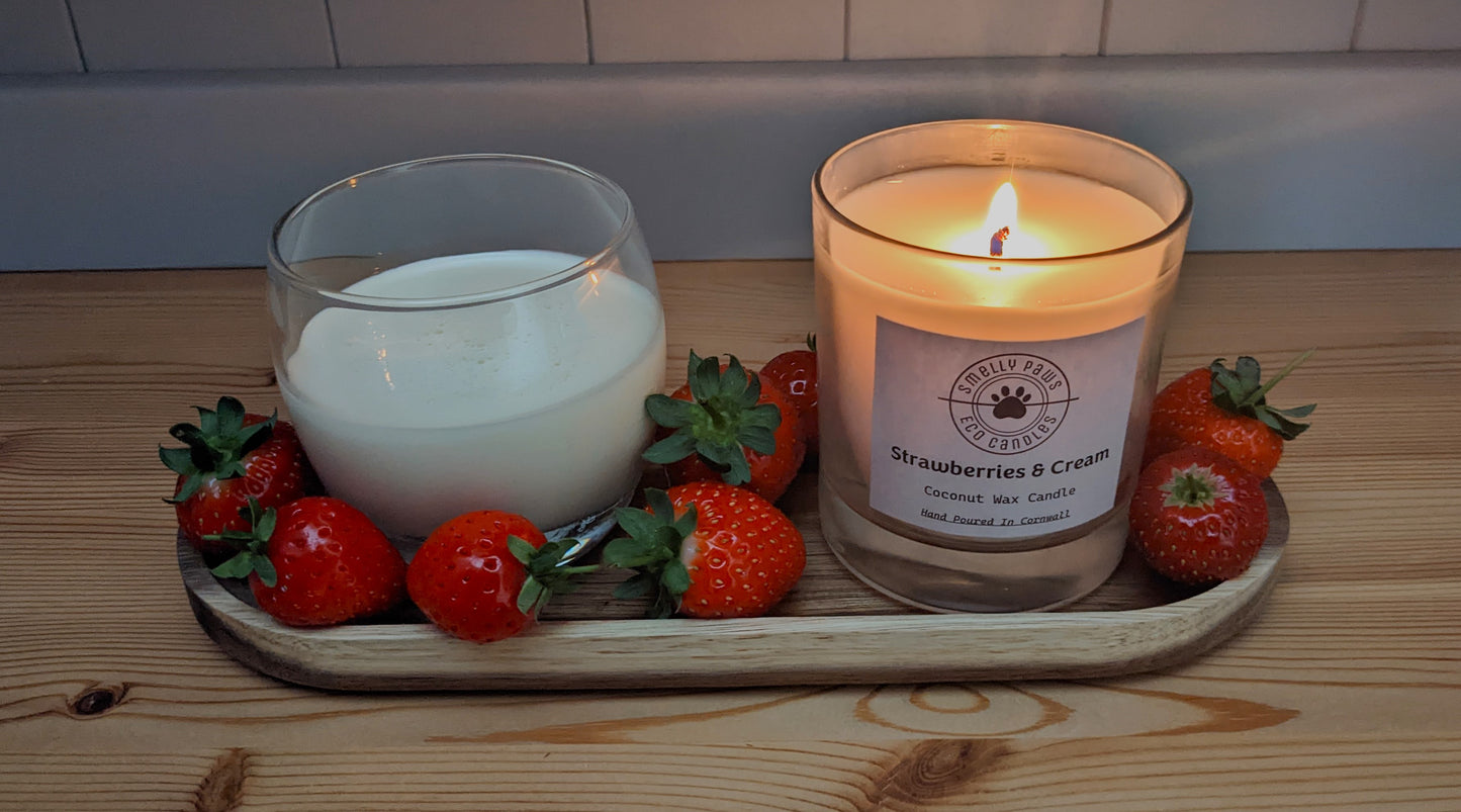 Burning Strawberries and cream candle sat on a wooden tray with a pot of cream and surrounded by Strawberries 